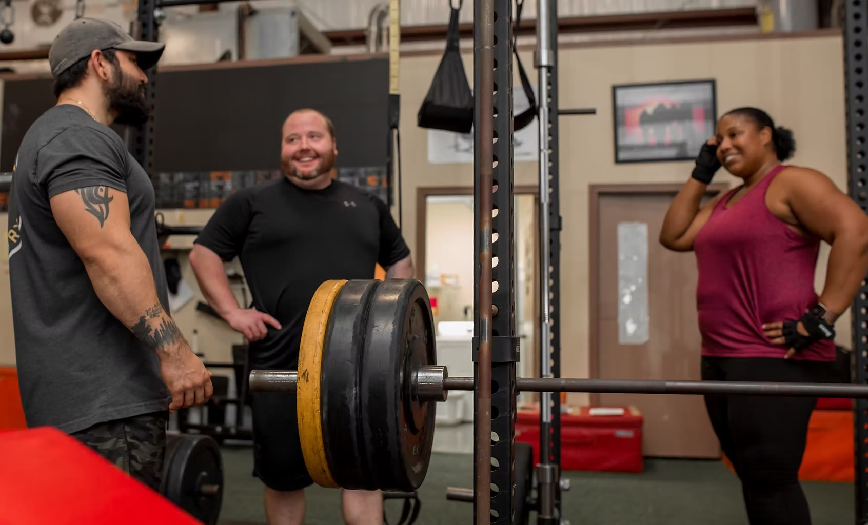 Martin in the gym with two clients standing at a loaded barbell